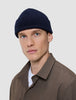 A man wearing a Wool Beanie Navy, a navy blue merino wool rib knit beanie.