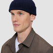 A man wearing a navy blue rib knit Wool Beanie Navy.