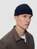 A person wearing a navy blue rib knit Wool Beanie Navy.