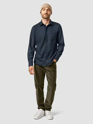 A man wearing a Beanie Khaki, a dark blue button-down shirt, olive green pants, and white sneakers.