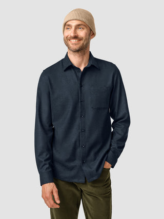 A smiling man wearing a dark navy long-sleeve button-down shirt and a Beanie Khaki.