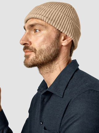 Profile view of a man with a beard wearing a Beanie Khaki and a dark collared shirt.