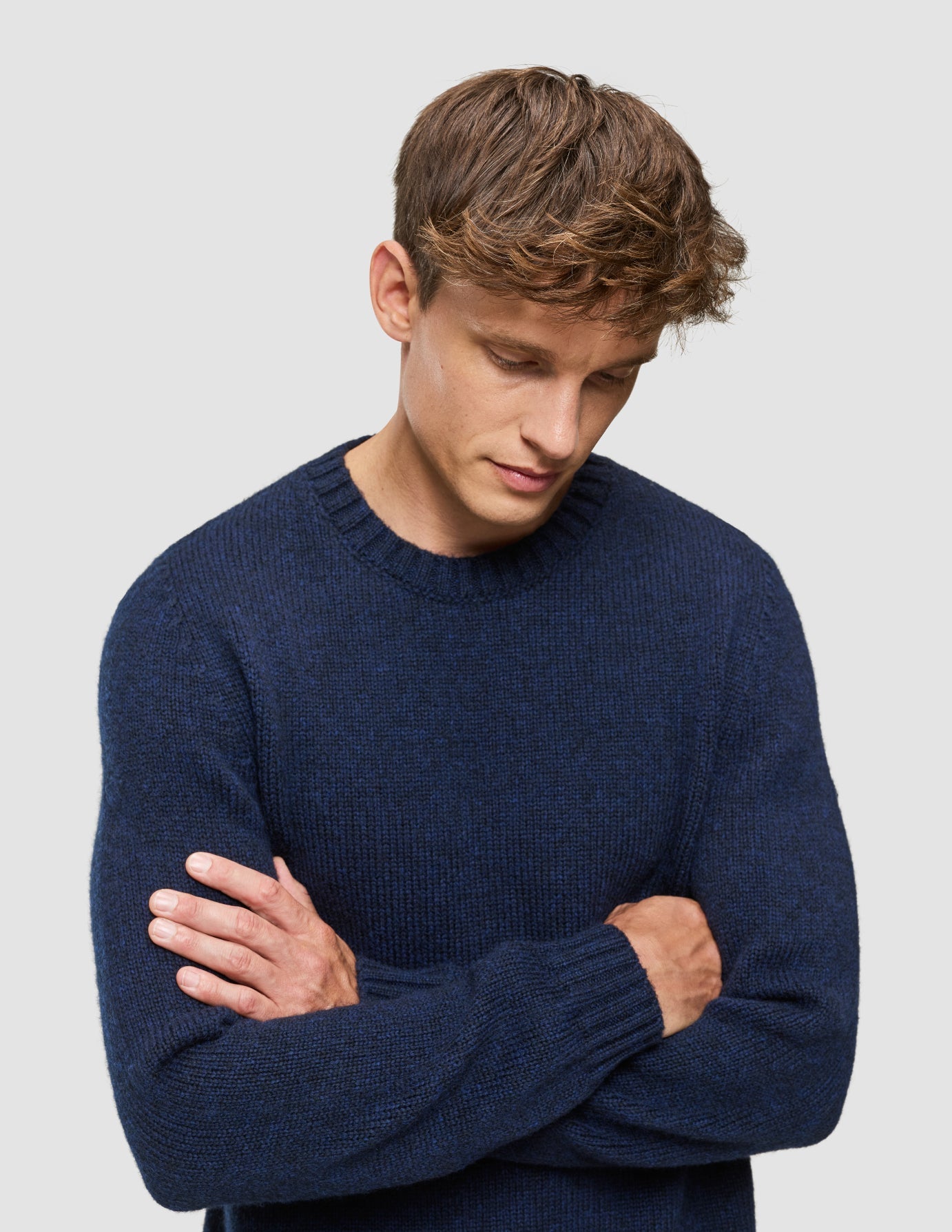 A man with his arms crossed wearing a Chunky Soft Wool Knit Crewneck Dark Navy Melange with a Scandinavian design.
