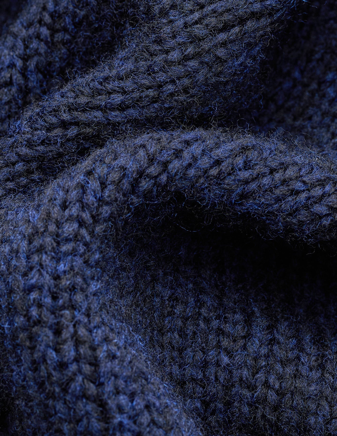 Close-up of the Chunky Soft Wool Knit Crewneck Dark Navy Melange, a chunky navy blue merino wool sweater with a visible ribbed texture.