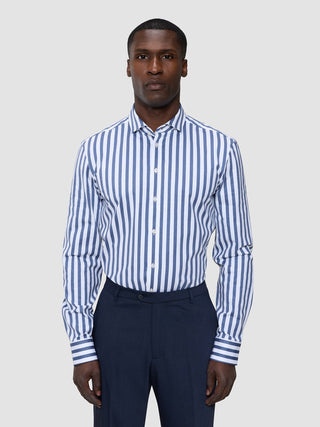 A man wearing a Classic Shirt Dusky Blue Stripe Regular tucked into dark trousers.