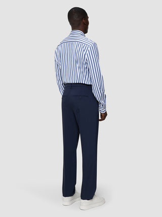 A man seen from behind wearing a Classic Shirt Dusky Blue Stripe Regular, navy trousers, and white sneakers.