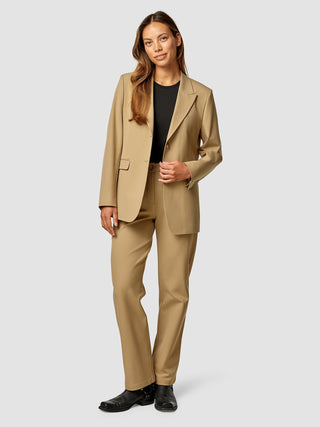 A woman wearing an Essential Blazer Caramel and matching trousers over a black top.