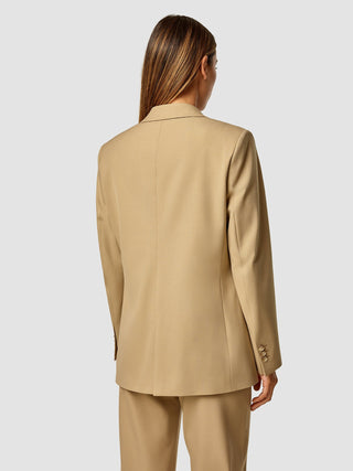 A woman from behind wearing an Essential Blazer Caramel.