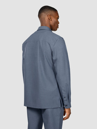 A man seen from behind wearing a versatile Essential Overshirt Storm Blue Melange and matching trousers.