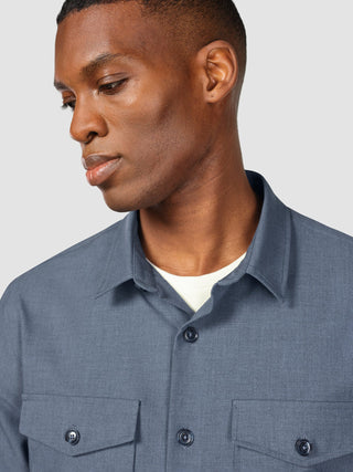 A man wearing an Essential Overshirt Storm Blue Melange over a white crew-neck undershirt.