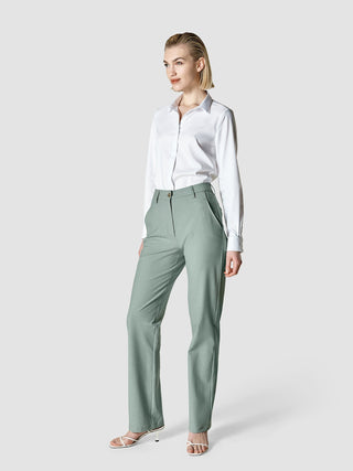 A woman wearing a white button-down shirt and Essential Pants Straight Calm Green Melange.