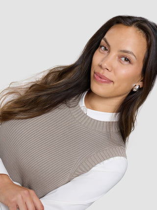 A woman poses against a plain background wearing a white collared shirt and a Women’s Fine Knit Rib Vest Dark Sand.