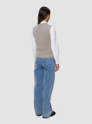 A woman from behind wearing a Women’s Fine Knit Rib Vest Dark Sand over a white collared shirt and blue jeans.
