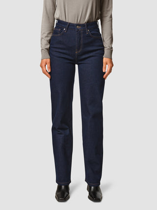 A person wearing a grey long-sleeved shirt tucked into Jeans Straight Fit Dark Blue and black boots.