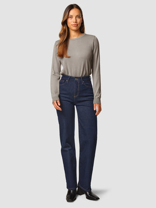 A woman wearing a long-sleeved gray crew-neck shirt tucked into Jeans Straight Fit Dark Blue.