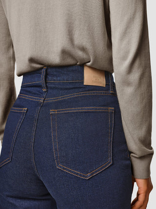 A person wearing Jeans Straight Fit Dark Blue with a Shaping New Tomorrow brand label on the waistband.