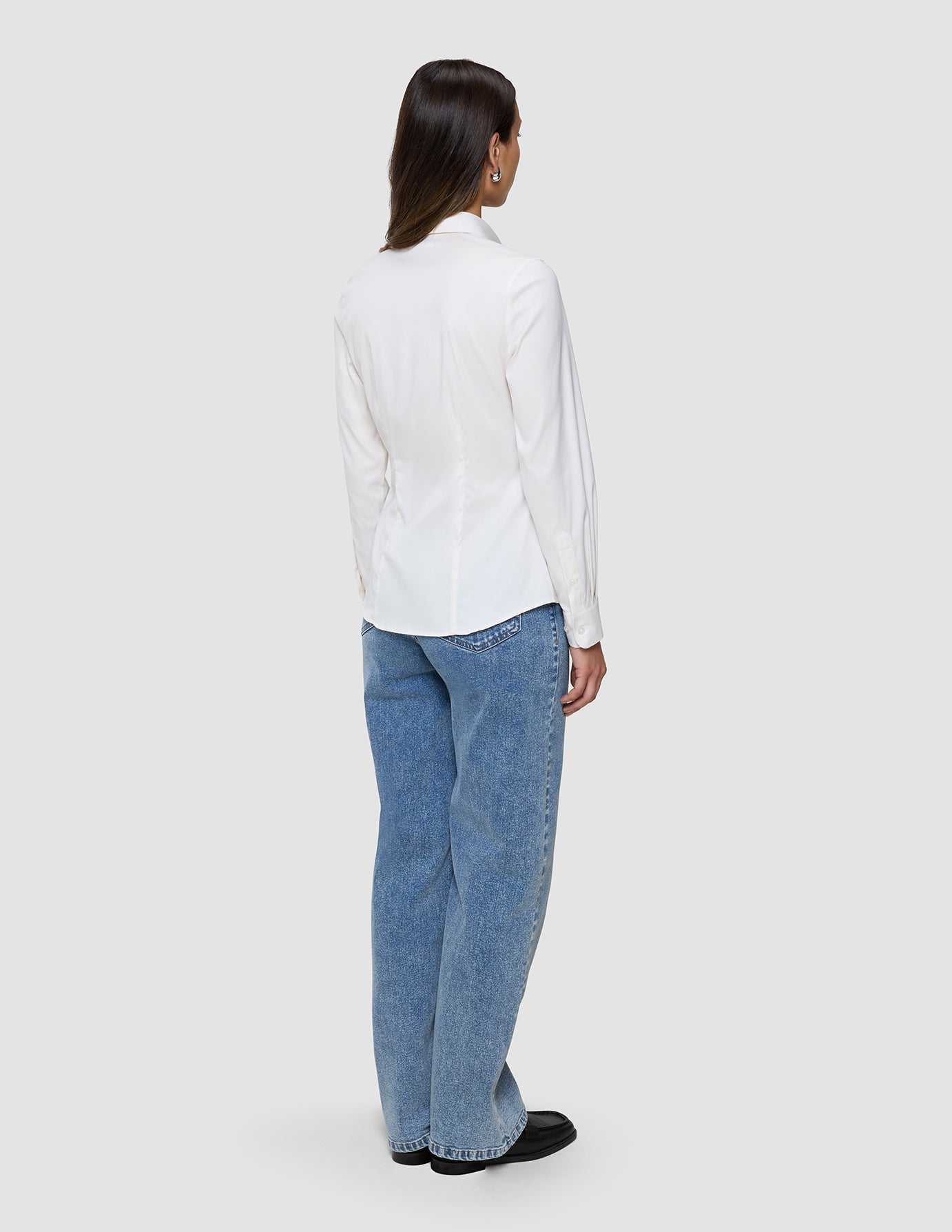 A woman seen from behind wearing a Women’s Oxford Shirt White Orchid Slim and blue jeans.