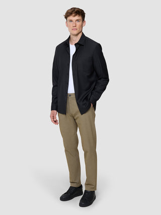 A man wearing a white t-shirt, an open Siena Shirt Black, tan trousers, and black sneakers styled with a Scandinavian design aesthetic.