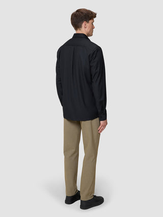 A man seen from behind wearing a Siena Shirt Black, tan trousers, and black sneakers.