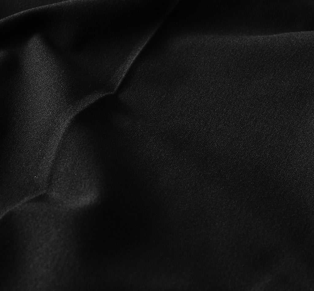 A close-up view of black fabric with soft folds.