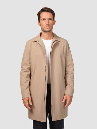 A man wearing a Waterproof Trench Coat Sand Grain over a white t-shirt.