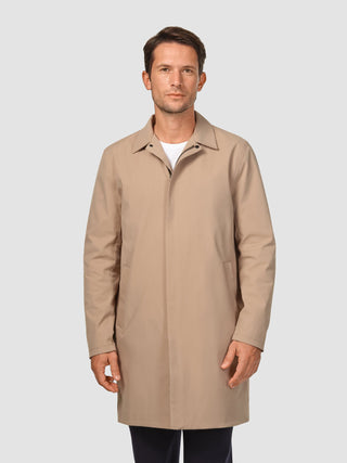 A man wearing a Waterproof Trench Coat Sand Grain over a white t-shirt and dark trousers, designed with a clean, Scandinavian aesthetic.