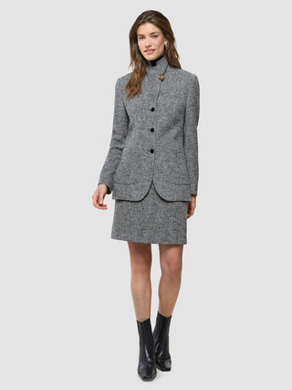 A woman wearing a Women Ashryn Blazer Domino Herringbone with a matching skirt over a black turtleneck and black boots.