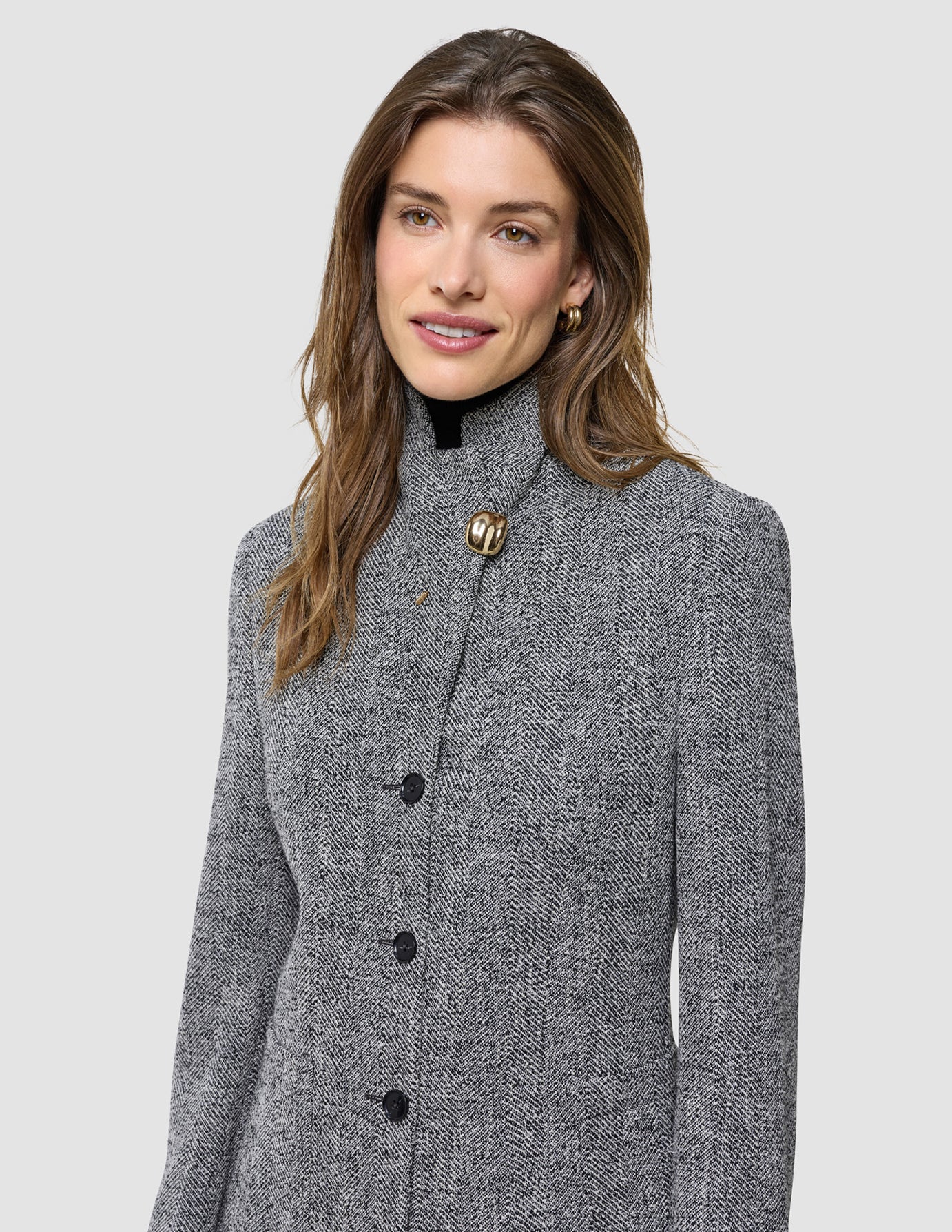 A woman wearing the Ashryn Set Domino Herringbone Blazer with a prominent gold button at the neckline.