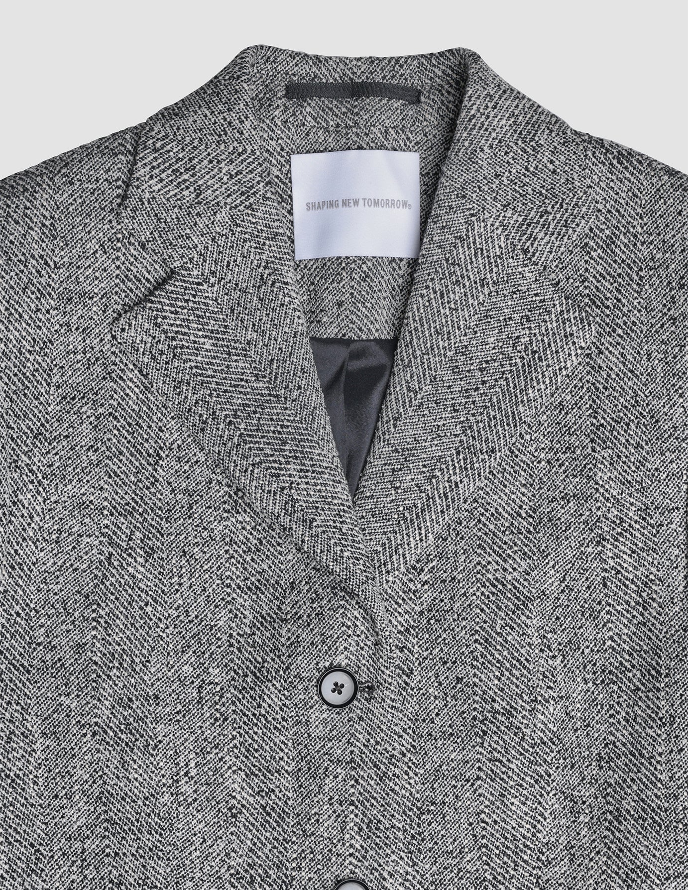 An Ashryn Set Domino Herringbone Blazer in Scandinavian design with a Shaping New Tomorrow brand label at the collar.