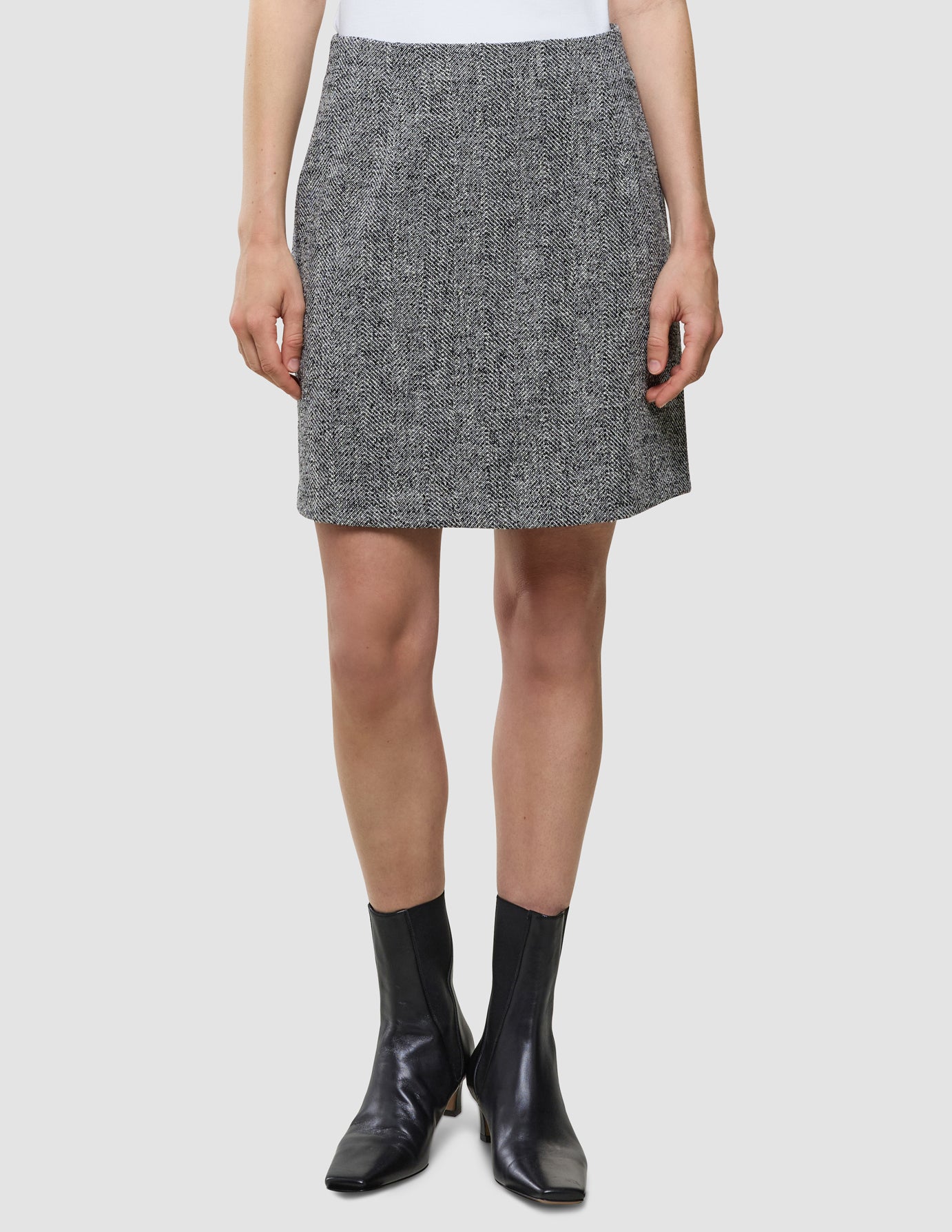 A person wearing an Ashryn Set Domino Herringbone Blazer and Short Skirt and black ankle boots.