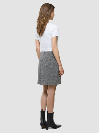 A person seen from behind wearing a white t-shirt, a Women Ashryn Short Skirt Domino Herringbone, and black boots.
