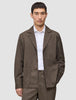 A man wearing a dark beige Atelier Overshirt heavyweight twill blazer over a white collared shirt.