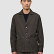 A man wears the Atelier Overshirt Dark Brown, a heavyweight textured blazer featuring three front buttons and two large patch pockets.
