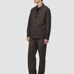 A person wearing a heavyweight, textured dark brown Atelier Overshirt and matching trousers over a black shirt.