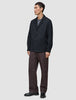 A person wearing a heavyweight, textured Atelier Overshirt Dark Navy over a grey t-shirt, paired with brown trousers and black loafers.