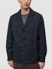 A person wears the Atelier Overshirt Dark Navy, a dark navy overshirt blazer in a heavyweight textured fabric featuring a notched collar and two patch pockets.