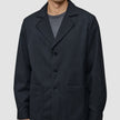 A person wears the Atelier Overshirt Dark Navy, a dark navy overshirt blazer in a heavyweight textured fabric featuring a notched collar and two patch pockets.