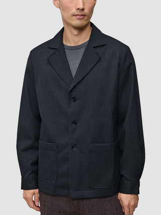 A person wears the Atelier Overshirt Dark Navy, a dark navy overshirt blazer in a heavyweight textured fabric featuring a notched collar and two patch pockets.