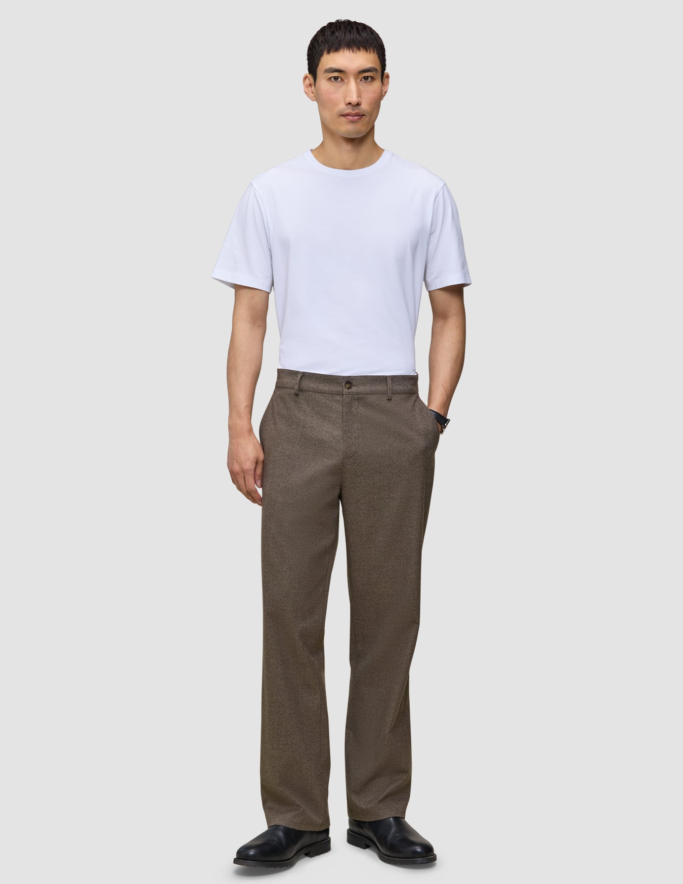 A man wearing a white t-shirt, black shoes, and Atelier Pants Relaxed Dark Beige in heavyweight broken twill.