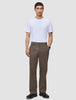 A man wearing a white t-shirt, black shoes, and Atelier Pants Relaxed Dark Beige in heavyweight broken twill.