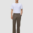 A man wearing a white t-shirt, black shoes, and Atelier Pants Relaxed Dark Beige in heavyweight broken twill.