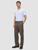 A man wearing a white t-shirt and Atelier Pants Relaxed Dark Beige in a heavyweight broken twill, finished with black leather shoes.