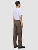 A man seen from behind wearing a white t-shirt and Atelier Pants Relaxed Dark Beige in heavyweight broken twill with black shoes.