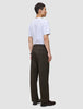 A man viewed from the side, wearing a white t-shirt and Atelier Pants Relaxed Dark Brown in heavyweight broken twill.