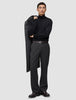 A man wearing a black turtleneck and Atelier Pants Relaxed Dark Grey in heavyweight broken twill, holding a coat over his shoulder.