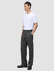 A man wearing a white t-shirt and dark grey Atelier Pants Relaxed in heavyweight broken twill, with his hand in his pocket.