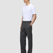 A man wearing a white t-shirt and dark grey Atelier Pants Relaxed in heavyweight broken twill, with his hand in his pocket.