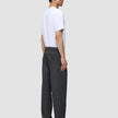 Profile view of a person wearing a white t-shirt, leather loafers, and dark grey Atelier Pants Relaxed in a relaxed fit, heavyweight broken twill.