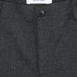 Close-up of the waistband and button of Atelier Pants Relaxed Dark Grey, featuring a white interior label that reads SHAPING NEW TOMORROW, SCANDINAVIAN DESIGN, HANDMADE IN PORTUGAL.