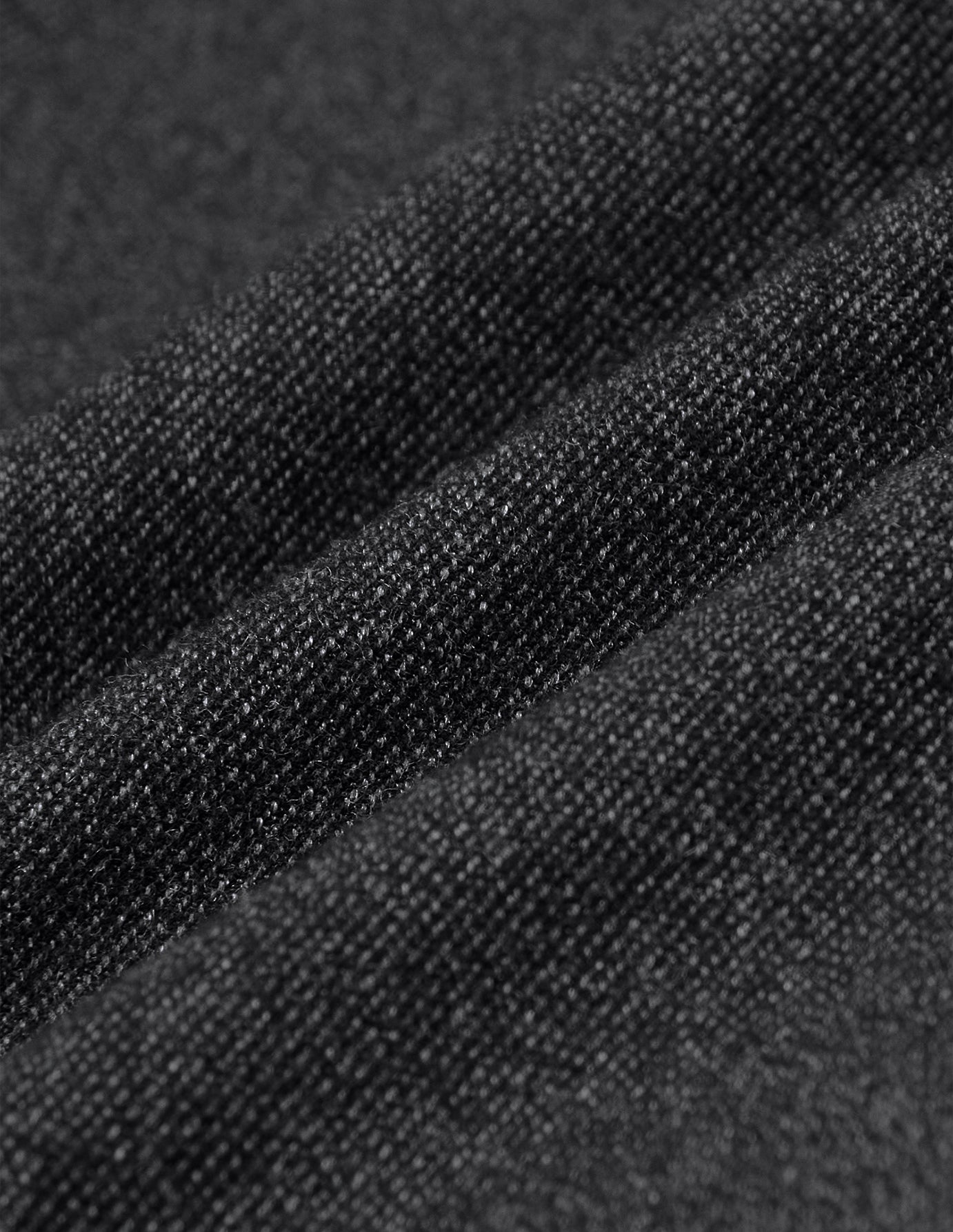 Close-up of dark grey Atelier Pants Relaxed in heavyweight broken twill fabric, featuring prominent diagonal folds and a textured finish.
